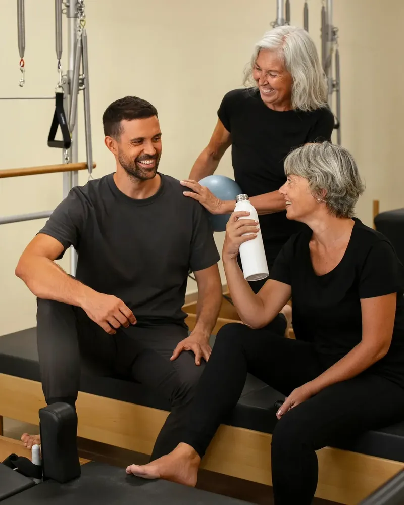 Trainer laughing with two older women during a session in the rehab studio
